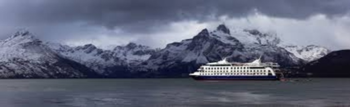 Crucero de expedición en canal antártico con témpanos y cordillera al fondo